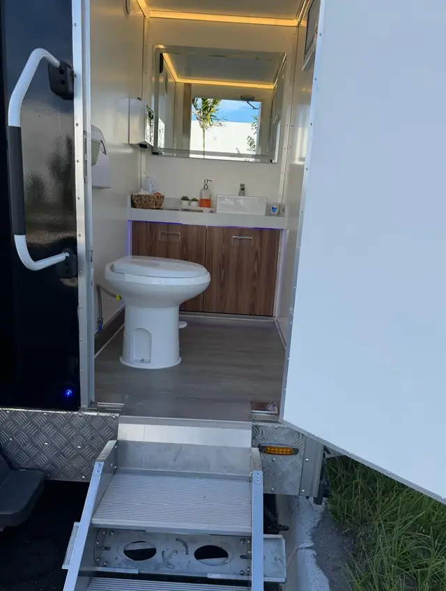 Restroom trailer stall with toilet and wood vanity